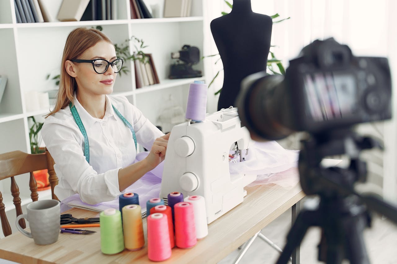 A fashion designer focused on sewing with colorful spools in a modern studio.